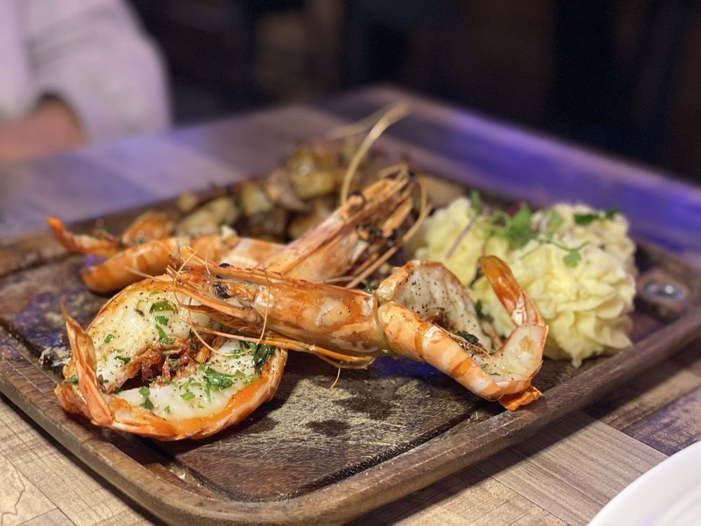 Jumbo prawns with mashed potatoes served on a wooden board