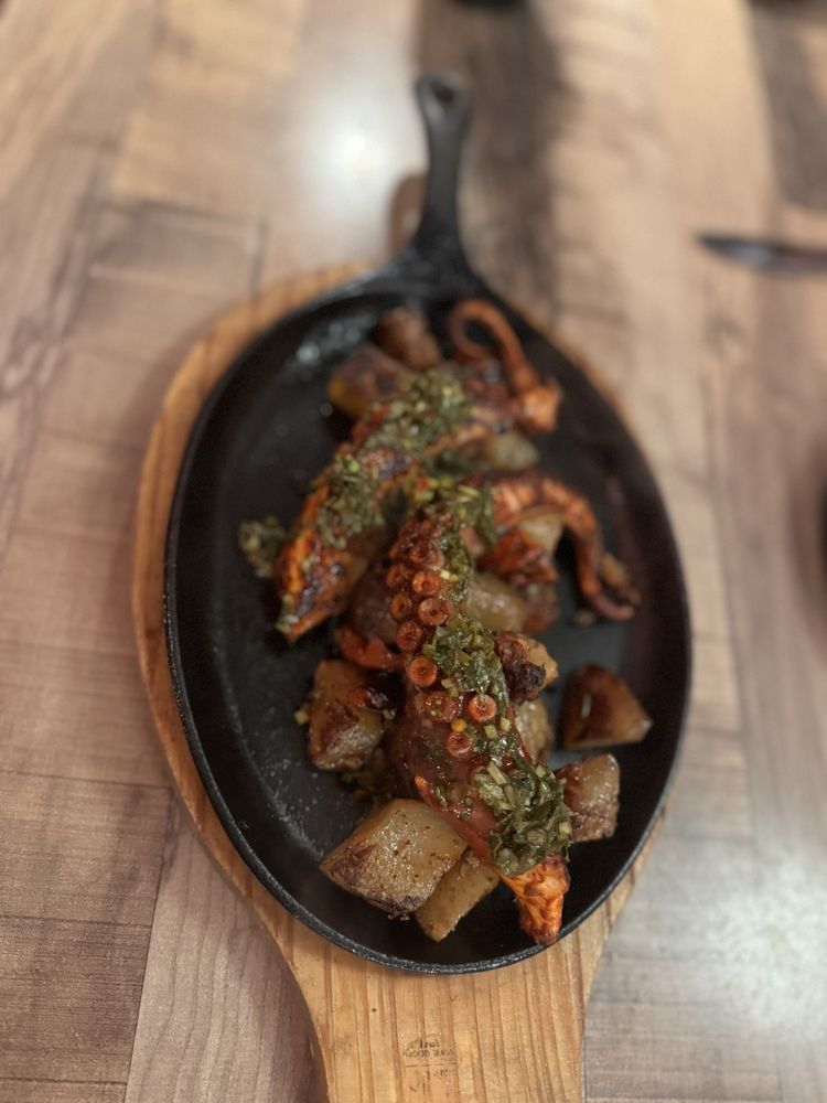 Grilled octopus with chimichurri and potatoes on a cast-iron skillet at Why Not?